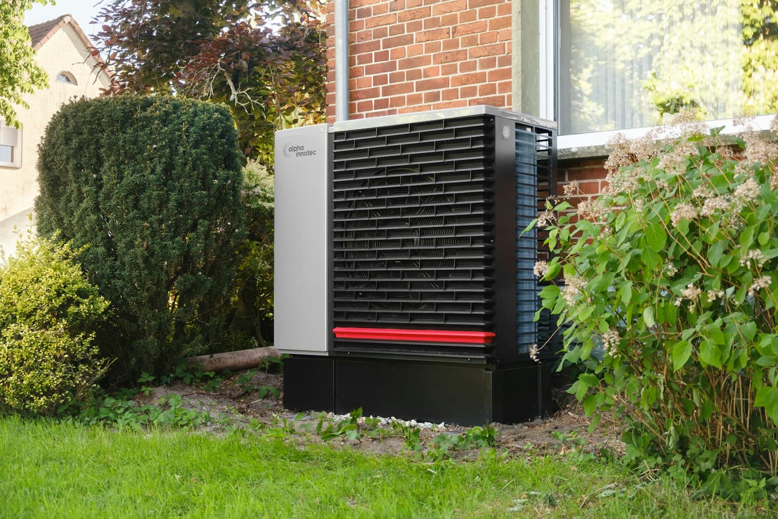 Compact new outdoor residential HVAC unit installed next to a brick home with autumn landscaping