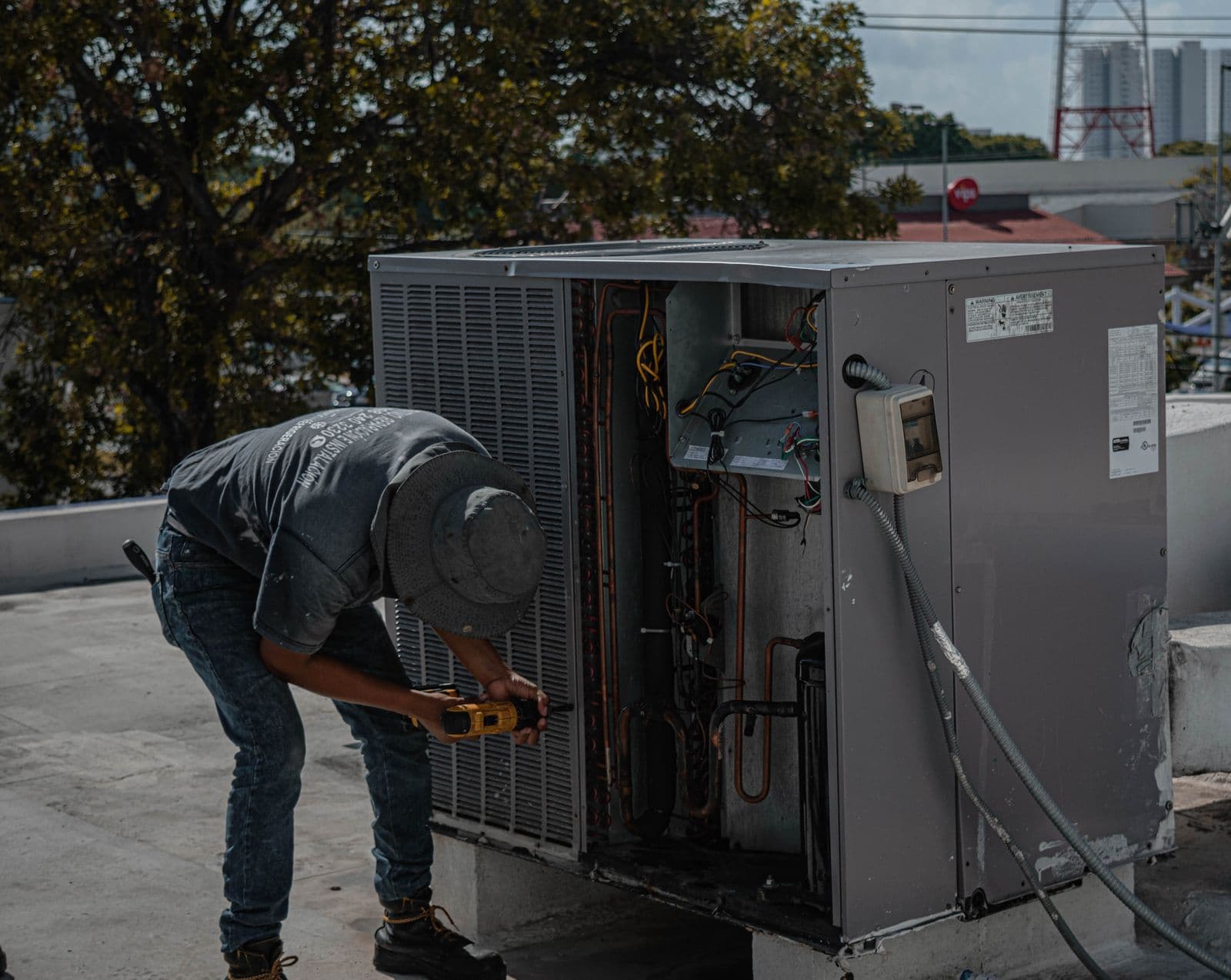 HVAC technician servicing an outdoor air conditioner unit with an open access panel during a seasonal tune-up