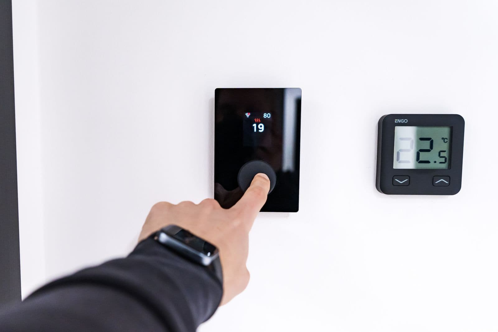 Hand pressing the touchscreen of a modern smart thermostat while troubleshooting a furnace that stopped blowing hot air